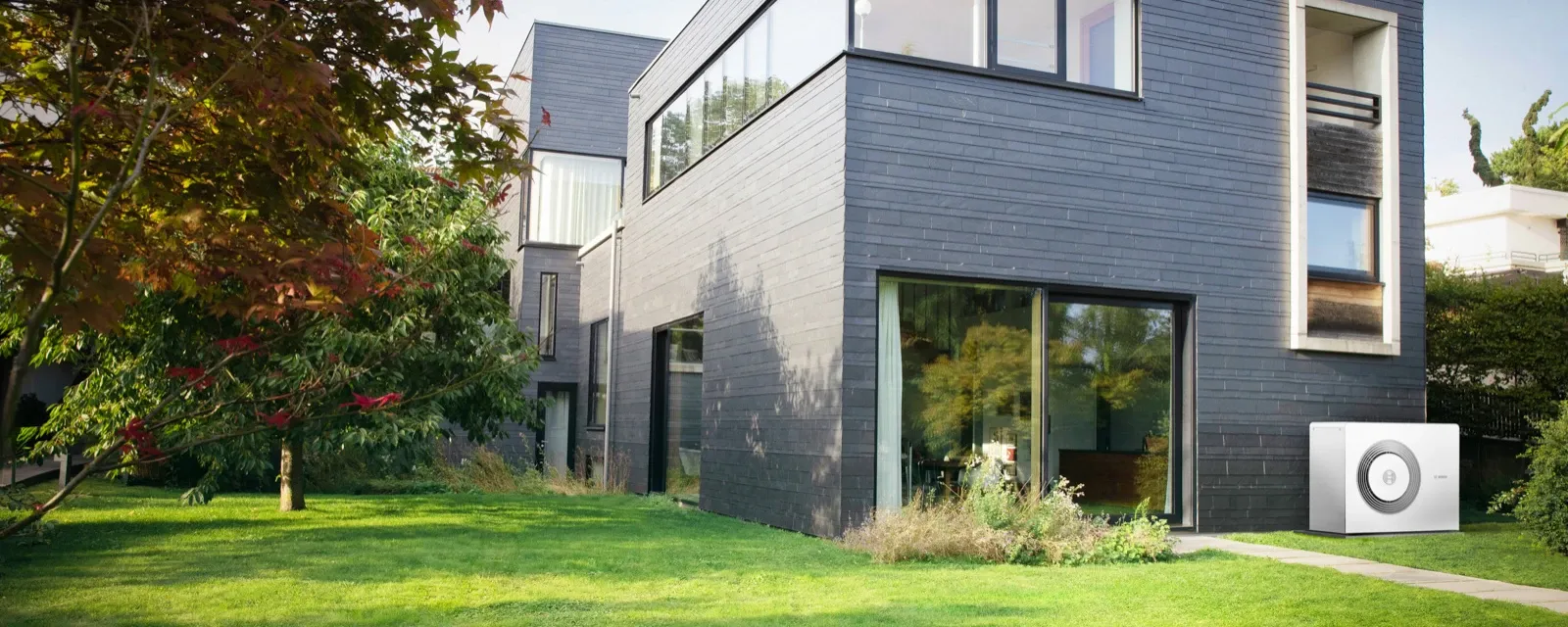 Bosch Wärmepumpe Compress an einem modernen Einfamilienhaus mit Garten